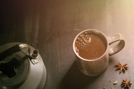 metal thermo mug with coffee on a gray background next to a teapot and star aniseの写真素材