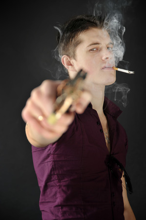 Rude  man with a cigarette in his mouth aiming a gunの写真素材