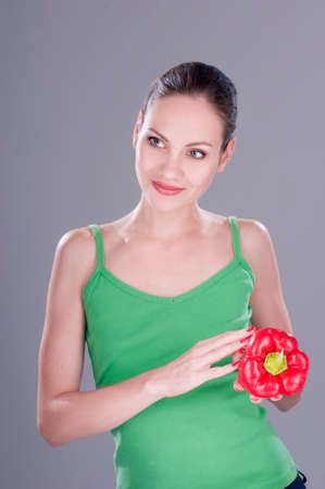 Young pretty woman with red pepper over gray background.の写真素材
