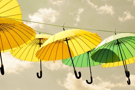 Yellow and green umbrellas  hanging under a gray sky.の写真素材