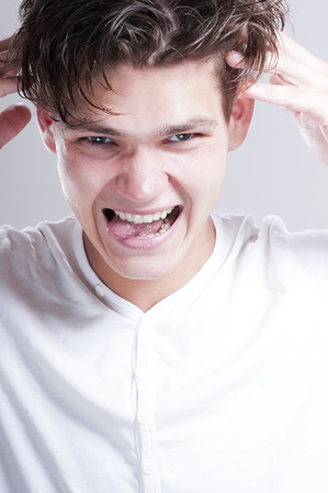 Seductive young man fooling around on camera, over gray background.の写真素材