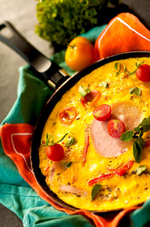 fried omelette with ham on pan.