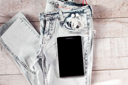 Tablet, earphones, jeans folded on the wooden boards.の写真素材