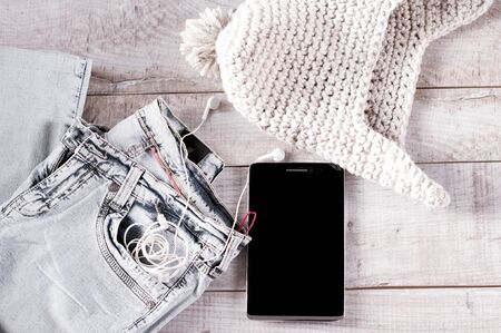 Different objects fot moder young person.  Tablet, earphones, jeans, knitted hat folded on the wooden boards.の写真素材