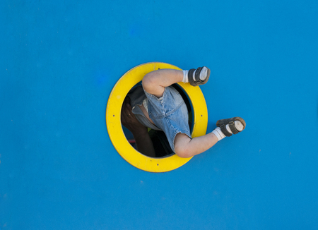 Funny kid playing in the playground. a child tries to climb through the ship's porthole.の写真素材