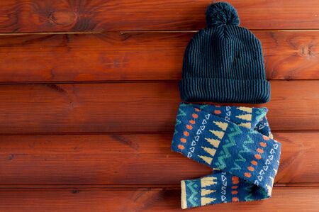 Kids' dark blue  hat  with a colorful scarf  lays  on wooden boards. free space for text.の写真素材