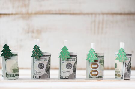 one hundred dollars rolls with clothespins decorated Christmas trees arranged in a line. Free space for greeting text.の写真素材