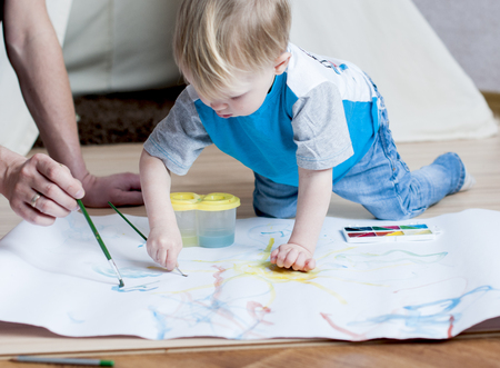 Adorable  small boy  tries to paint with watercolors at homeの写真素材