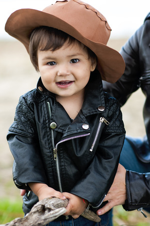 portrait of a delightful little girl in a brown hat and a black leather jacketの写真素材