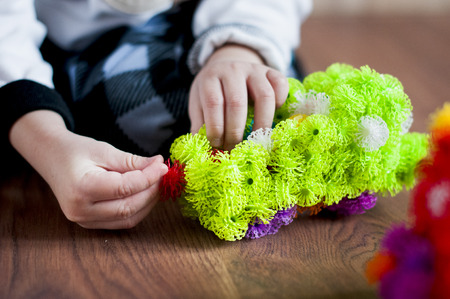 The child plays with the designer Velcro on floor indoors. He constructs from a green plastic rugby machineの写真素材