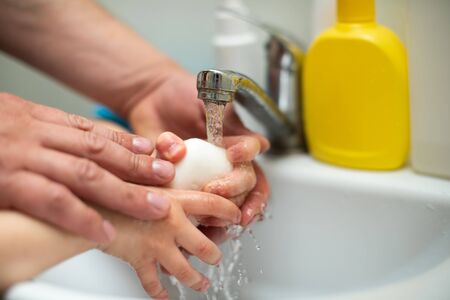 Father washes hands with soap to little son for coronavirus prevention