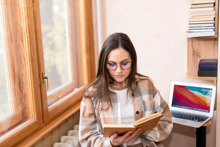 Female freelancer with long dark hair wearing glasses reading a book