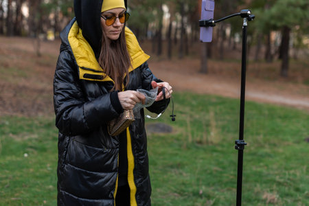 Female blogger preparing to record video on phone with tripod in open areaの写真素材