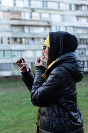 A girl fixes her makeup on the street - uses a mirror and a lipstickの写真素材