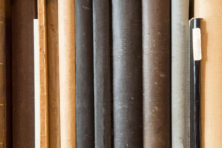 Many old dusty books in a library on a wooden shelve