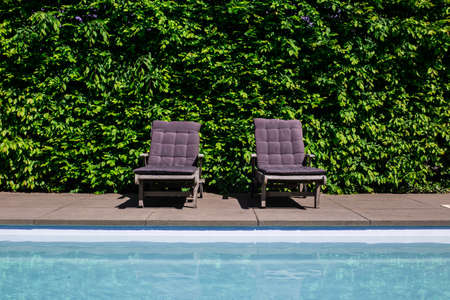 Blue luxury swimmingpool of a modern villa with a couch on a hot summer dayの写真素材
