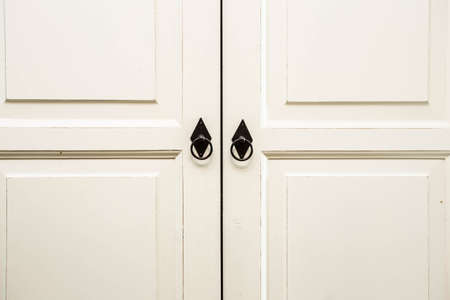 Vintage white wooden cupboard doors with metal handlesの写真素材