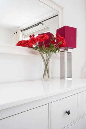 Beautiful flowers with table lamp on white wall background with beautiful mirror modern interior in...