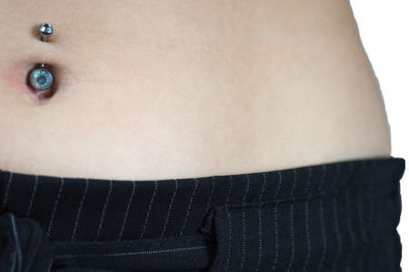 Detail of the belly of a young woman, wearing a navel piercing