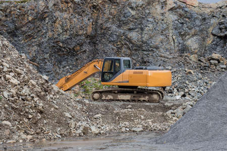 A large construction excavator of yellow color on the construction site in a quarry for quarrying