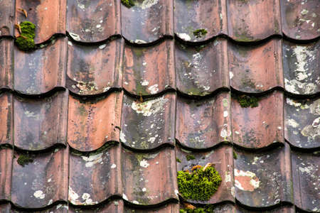 Old and ruined roof tiles close-up. Texture of a roof with old roof tiles.
