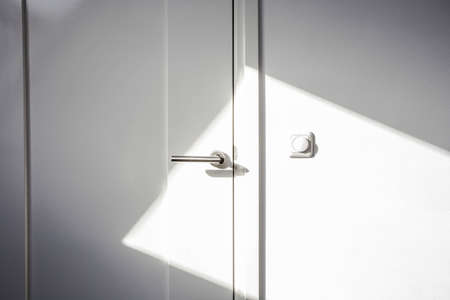 Close-up white door with sunlight. Chrome door ,The light switch on the wall modern design empty and cleanの写真素材