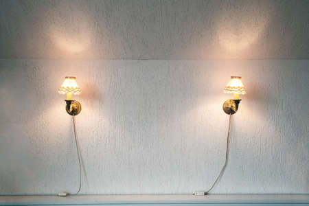 Two vintage lamps on the wallpaper . Wall light of gilded metal with two electric candles