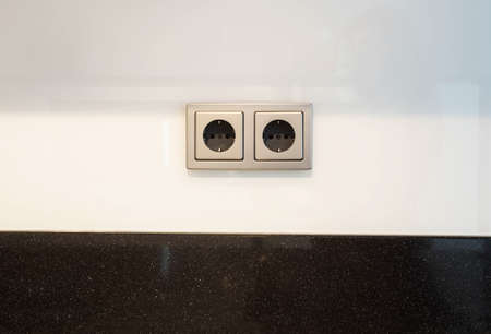 European white electrical outlet socket and black cable plugged in isolated on white wallの写真素材