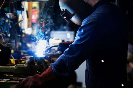Welder is welding in the garage,industrial Worker labourer at the factory welding steel structure