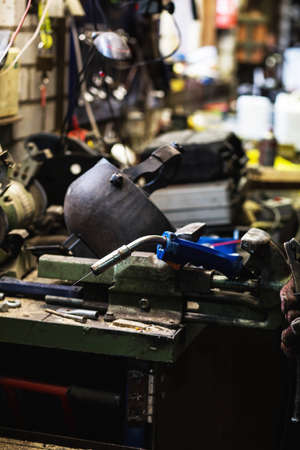 welder is welding metal part in garage. with protective mask, industrial steel welder