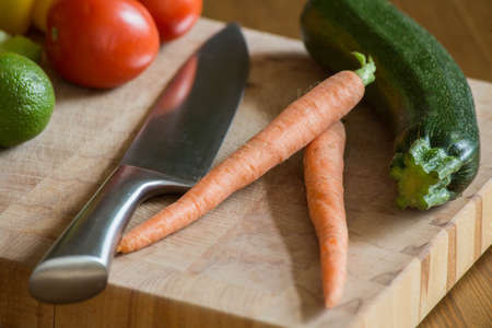 fresh vegetables on the cutting board and knife onion, tomatoes,carrot lemons., paprika, on wood backgroundの写真素材