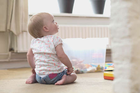 Baby playing alone with toys on a carpet on the floor at home messy