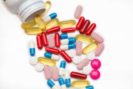 Assorted pharmaceutical medicine pills, tablets and capsules and bottle on white background. Copy...