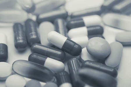 Assorted pharmaceutical medicine pills, tablets and capsules and bottle on white background. Copy...