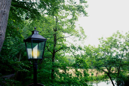 Old lantern on the background of green trees in a park beautyの写真素材