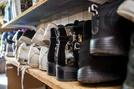 Small shoe rack fully filled with many shoes, sneakers and sandals. Too many shoes make the shoe...