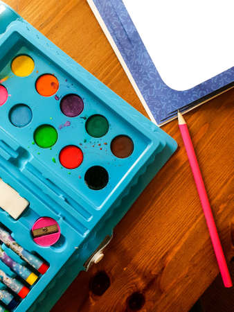 painting stuff of little girl painting in the living room in her pink dress on wooden tableの写真素材