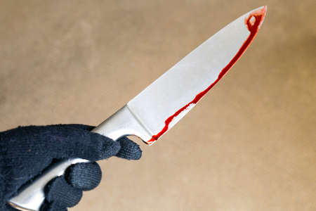 murder and crime scene concept - close up of criminal or murderer hand in glove with blood on knife