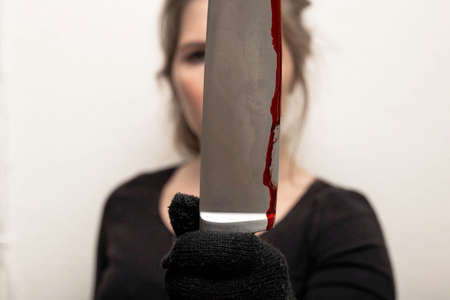 young woman holding bloody knife with black glove , crime scene killing