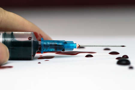 Hand lying on the floor with a Syringe splashing blood, scary theme suicide or overdose isolatedの写真素材
