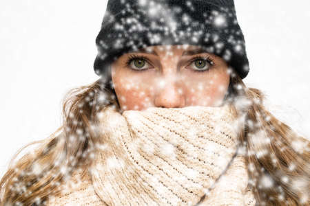 Woman in the Snow with winter wearing, wrapped in winter cap and scarf looking cold isolated on white backgroundの写真素材