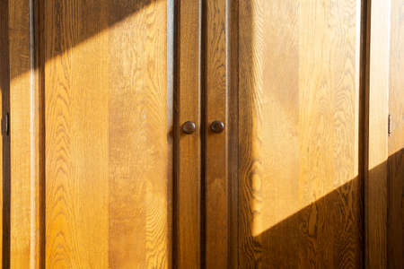 Brown wooden closet doors, oak luxury design beauty with sunlight and shadows closeupの写真素材