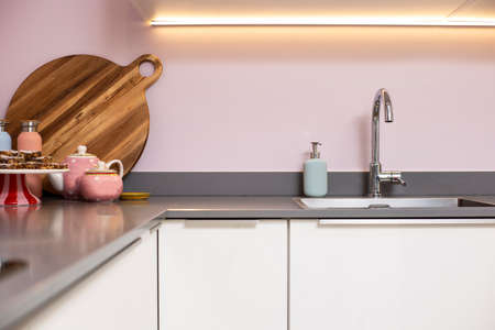 Close-up of a counter and modern kitchen. steel sink with pink wall and decoration modern light interiorの写真素材