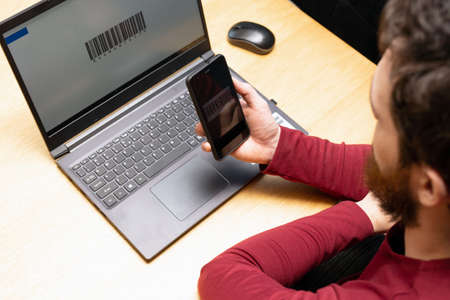 Person scanning with mobile phone, barcode on a computer screen, online modern payment with scanning app smartphoneの写真素材