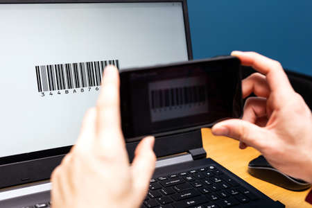 Person scanning with mobile phone, barcode on a computer screen, online modern payment with scanning app smartphoneの写真素材