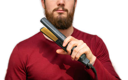 Portrait of man straightened his beard with a straightener, styling his beard on isolated white backgroundの写真素材