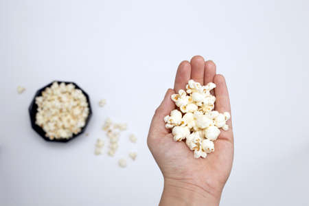 Person holding popcorn in hand top view, with popcorn in bowl isolated on white backgroundの写真素材