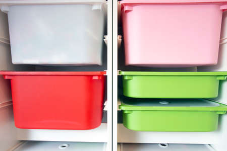 Stack of plastic storage boxes in different colors, sorting system arrangement close-upの写真素材