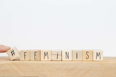 Wooden cubes with a hashtag and the word Feminism near white background, social media conceptの写真素材