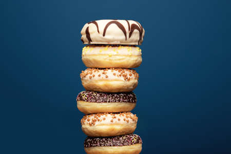 Stack of assorted delicious colorful donuts near dark blue background, sugar conceptの写真素材